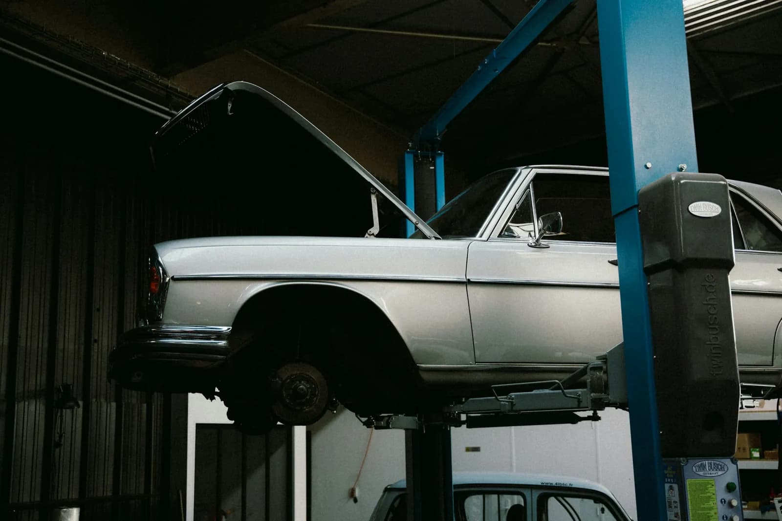 Silver vehicle raised on a service lift in a professional automotive workshop